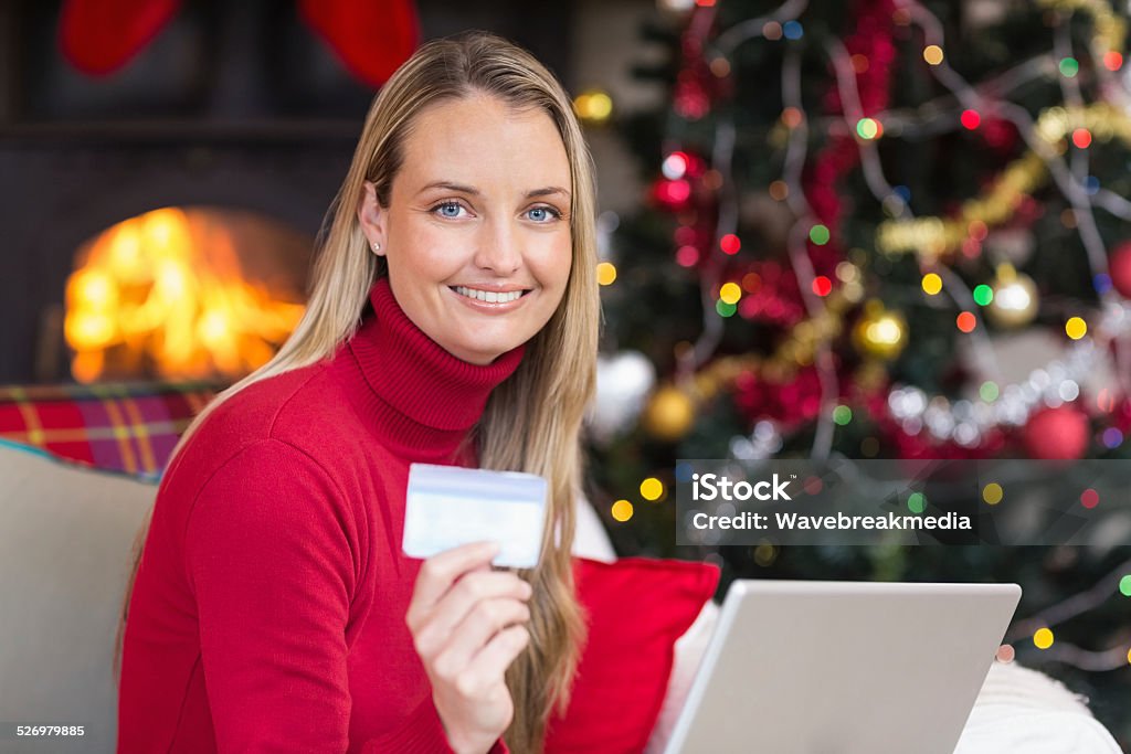 Blonde shopping online with laptop at christmas Blonde shopping online with laptop at christmas at home in the living room 30-34 Years Stock Photo