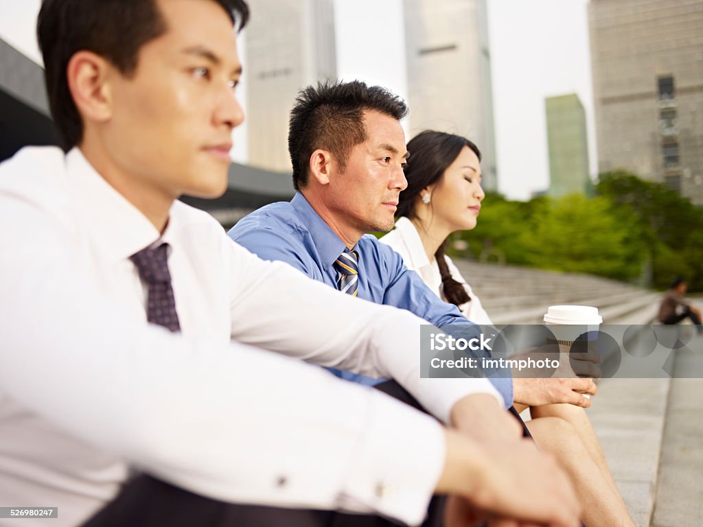 team of asian businesspeople looking frustrated and depressed three asian business people sitting on steps looking frustrated and depressed. click for more: 30-39 Years Stock Photo