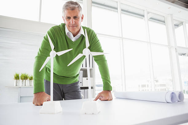 istock Casual businessman looking at model wind turbines 526981127
