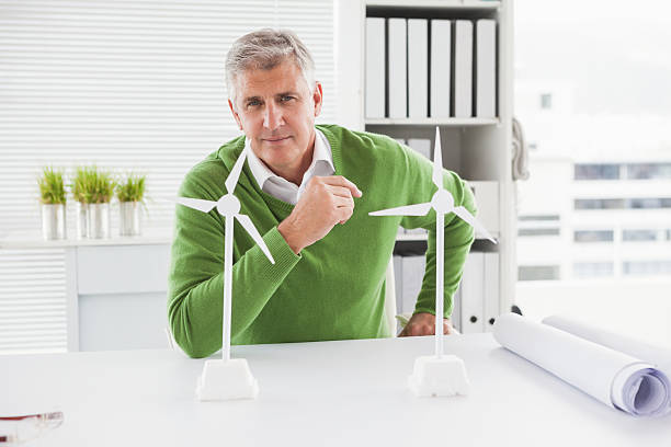 istock Casual businessman looking at model wind turbines 526981135