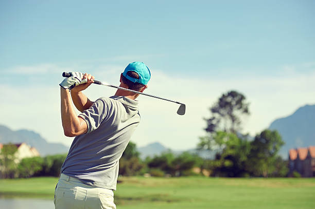 golf shot man Golfer hitting golf shot with club on course while on summer vacation swing stock pictures, royalty-free photos & images