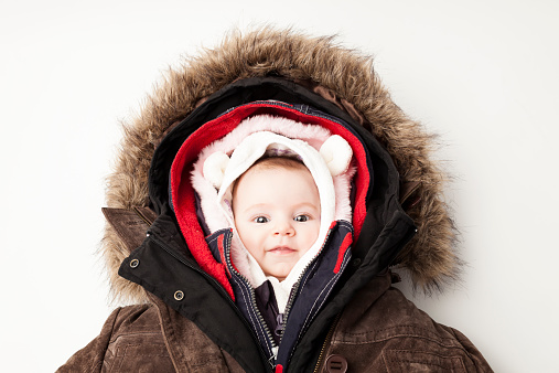 Concept Shot of a cute 3 month baby girl in many winter jackets.