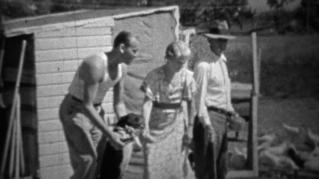 1934: Family plays with dog while man casually feeds chickens.