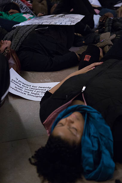Female protestor lies on floor next to protest signs New York City, USA - December 6, 2014: Demonstrators Lie on Floor of Grand Central Terminal to protest the deaths of Eric Garner and Michael Brown and the acquittals of the police officers who killed them. Chants of "I can't breathe" and "Hands Up, Don't Shoot!" where heard. i cant breathe photos stock pictures, royalty-free photos & images