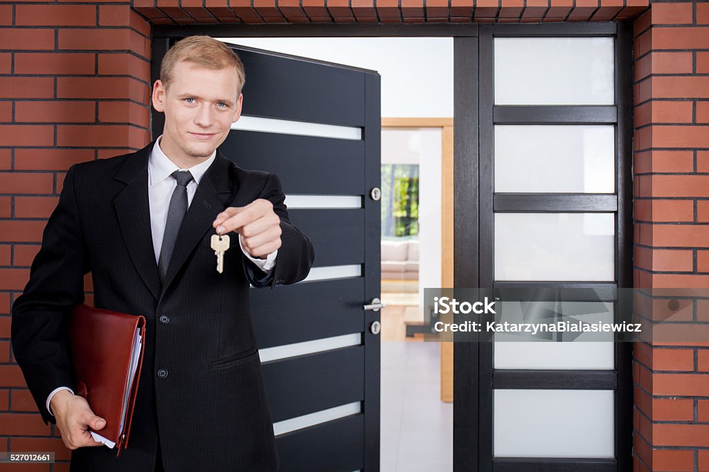 Standing in front of door House agent standing in front of door Adult Stock Photo