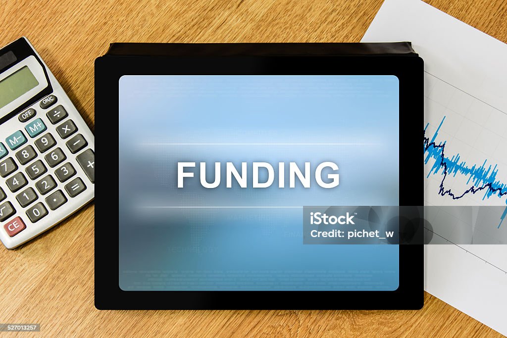 funding word on digital tablet funding word on digital tablet with calculator and financial graph Business Stock Photo