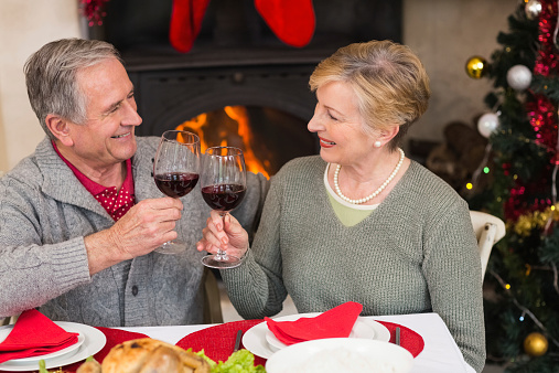 Senior couple toasting red wine at home in the living room