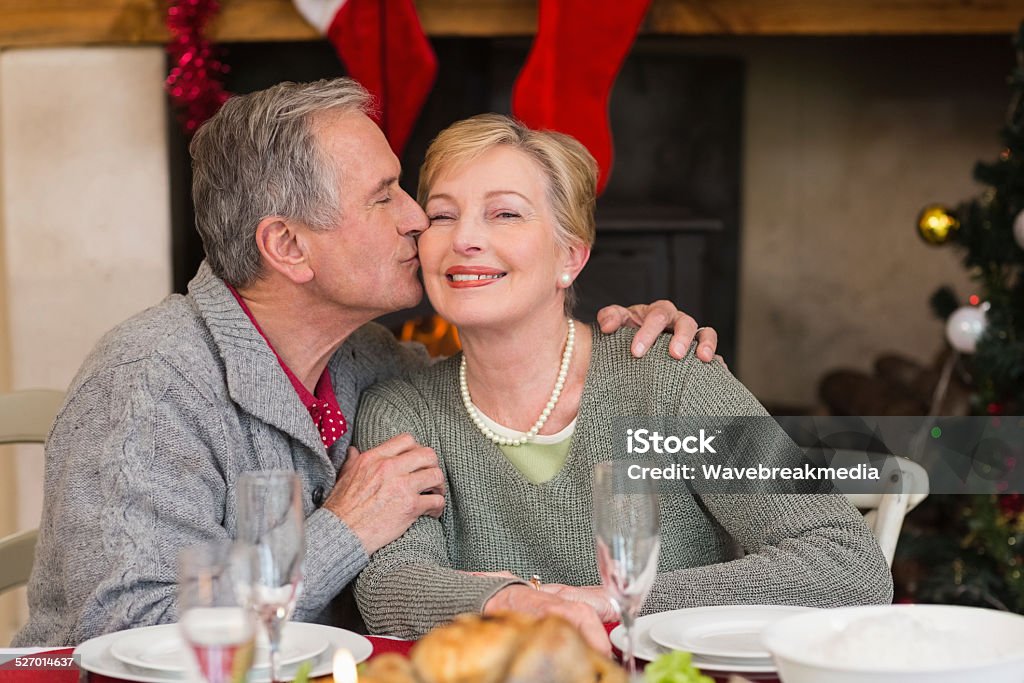 Hombre maduro besar a su esposa la mejilla - Foto de stock de 60-69 años libre de derechos