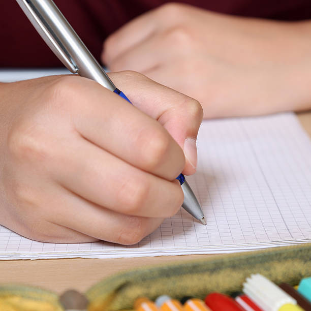 istock Student writing with hand in his exercise book at school 527014779
