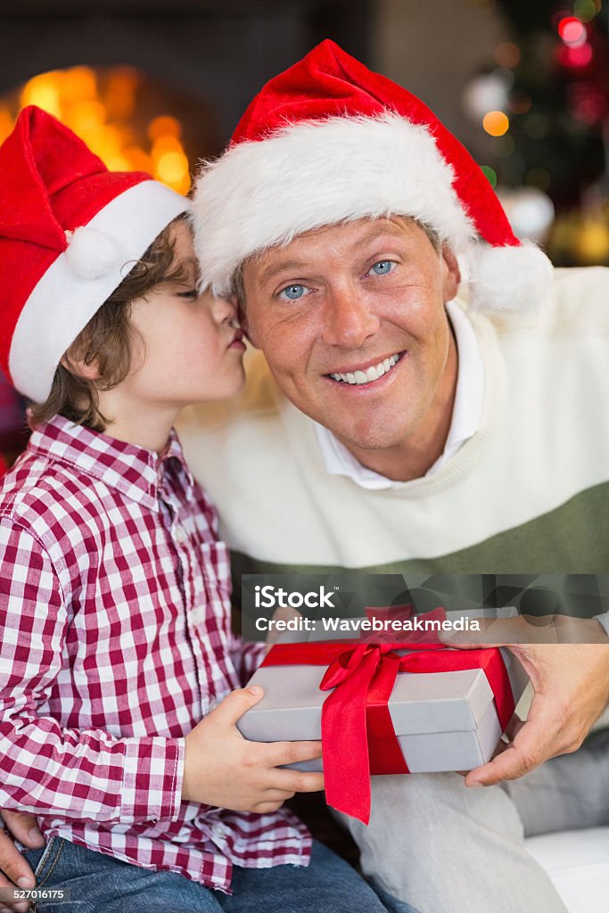 Son kissing his father after receiving a christmas gift Son kissing his father after receiving a christmas gift at home in the living room 40-44 Years Stock Photo