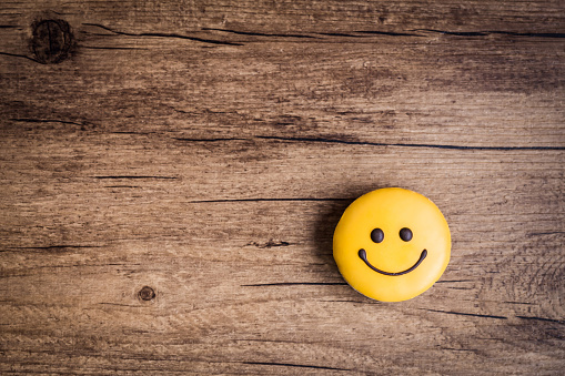 Blue happy face emoji surrounded by yellow happy face emojis. Horizontal composition.