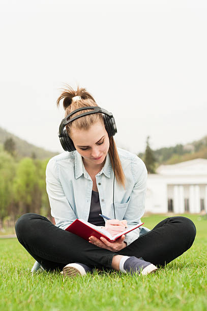 istock Smiling young girl writing on journal while sitting on grass 527041298