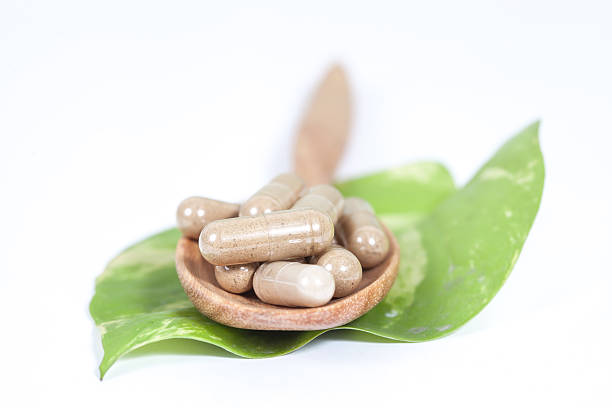 istock Capsules of herbs on spoon on white background 527043392