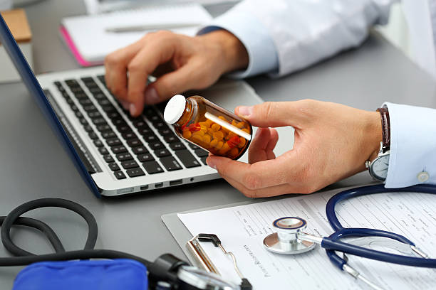 Male medicine doctor hands hold jar of pills Male medicine doctor hands hold jar of pills and type something on laptop computer keyboard. Panacea and life save, prescribing treatment, legal drug store, take stock, consumption statistics concept electronics store stock pictures, royalty-free photos & images