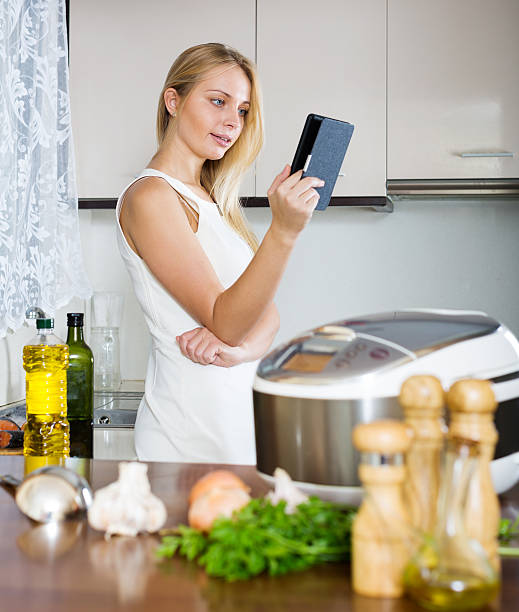 istock housewife reading ereader and cooking with multicooker 527048735