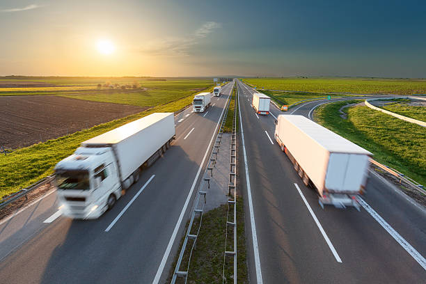 istock Big white trucks on highway towards the setting sun 527049258