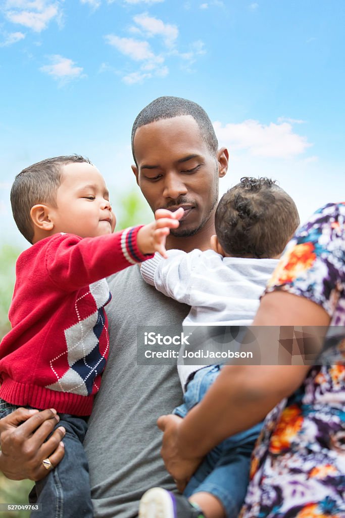 Grandmother helps her single father son with his twin boys Afro american family consisting of single father, grandmother, and twin boys. She is helping her son take care of his two year old twins.  Outside shot taken with a Canon 5D Mark 3 camera.  rm 18-23 Months Stock Photo