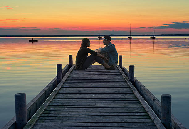 istock Young couple sitting on jetty at dusk 527051437