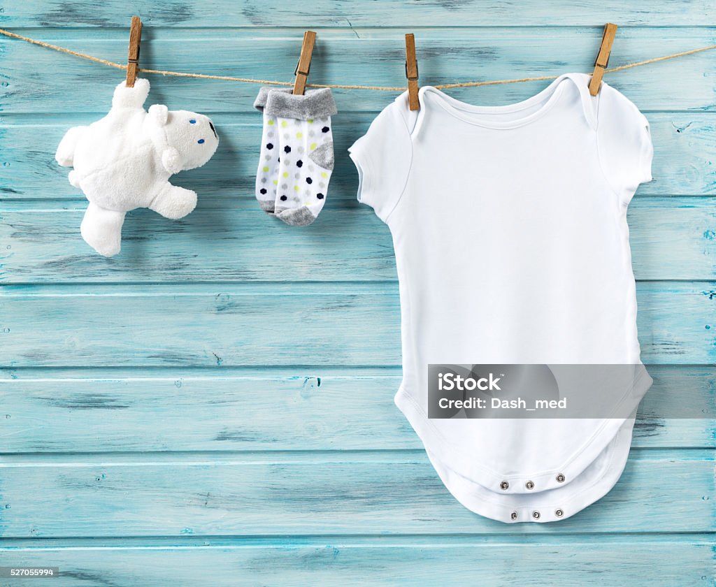 Baby boy clothes and white bear toy on a clothesline Baby boy clothes and white bear toy on a clothesline on blue wooden background Baby - Human Age Stock Photo