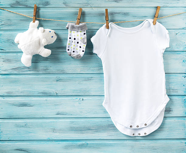 Baby boy clothes and white bear toy on a clothesline Baby boy clothes and white bear toy on a clothesline on blue wooden background babygro stock pictures, royalty-free photos & images