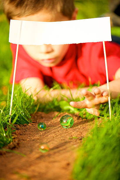 istock lying kid play with marbles in start line 527069163