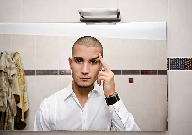 Handsome young man looking at himself in bathroom mirror, self point of view