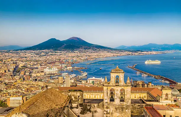 Scenic picture-postcard view of the city of Napoli (Naples) with famous Mount Vesuvius in the background in golden evening light at sunset, Campania, Italy.
