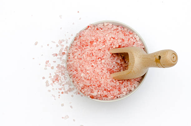bowl, rose bath salts, spoon, white background, top view bowl full of bath salts with pink and white grains, spoon to measure, grains of salt fallen, all isolated on white background top view bath salt photos stock pictures, royalty-free photos & images