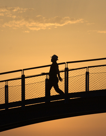 man with hat crossing a bridge