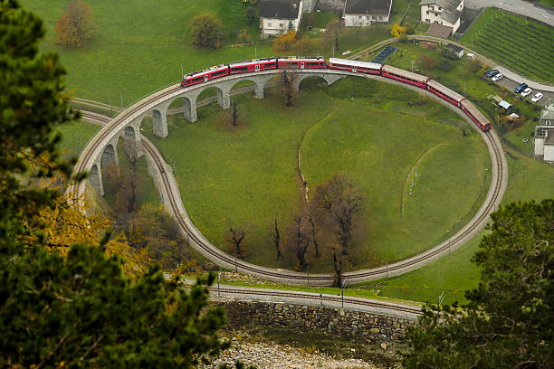 Brusio spiral viaduct Brusio, Switzerland, November, 9, 2014 : A train climbs the famous Brusio spiral viaduct engadine stock pictures, royalty-free photos & images