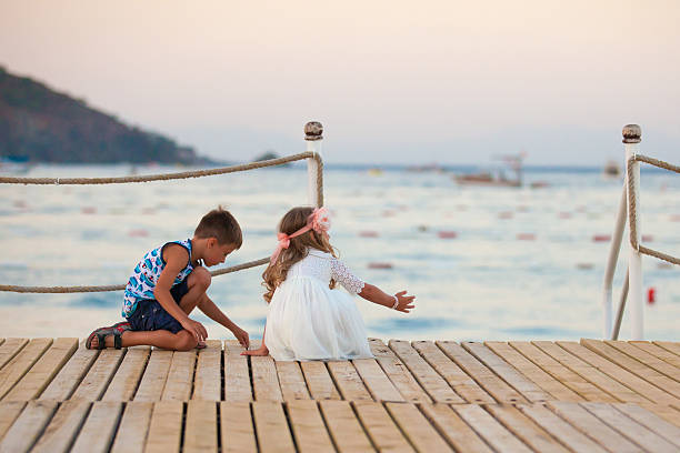 Girl and boy are sitting on th pier stock photo