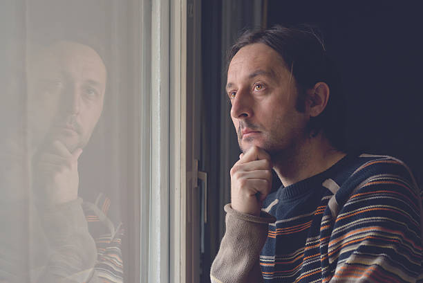 istock Sad man by the window 527086989