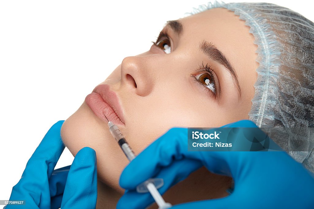 Beauty woman botox injections. Portrait of young woman getting cosmetic injection of botox, isolated over white background. Patient Stock Photo