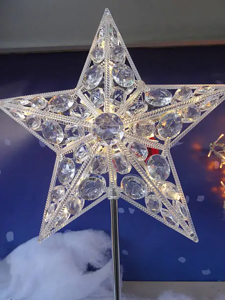 Photo of a star Christmas tree topper decoration, made with a silver rod and crystals to reflect the fairy lights on the tree itself.