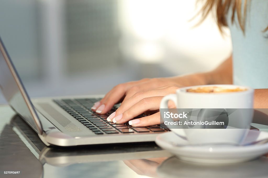 Woman hands typing in a laptop in a coffee shop Close up of a woman hands typing in a laptop in a coffee shop terrace in the street Adolescence Stock Photo