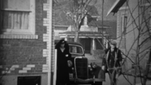 1936: Couple exits Lincoln car enters suburban brick home.