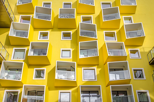 Architecture of a building with yellow walls and protuberant balconies in Ørestad, Denmark. 