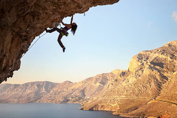 silueta de mujer joven rock climber sobre un acantilado - rock climbing mountain climbing women climbing fotografías e imágenes de stock