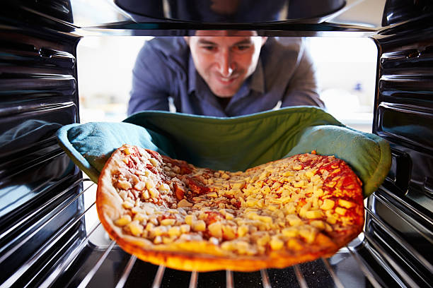 istock Man Putting Pepperoni Pizza Into Oven To Cook 527117393