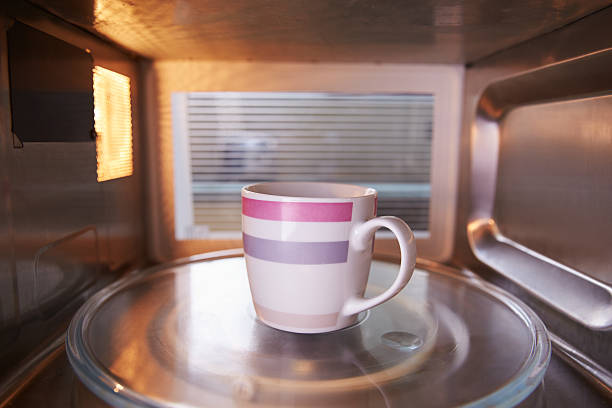 Warming Cup Of Coffee Inside Microwave Oven Warming Cup Of Coffee Inside Microwave Oven inside microwave stock pictures, royalty-free photos & images