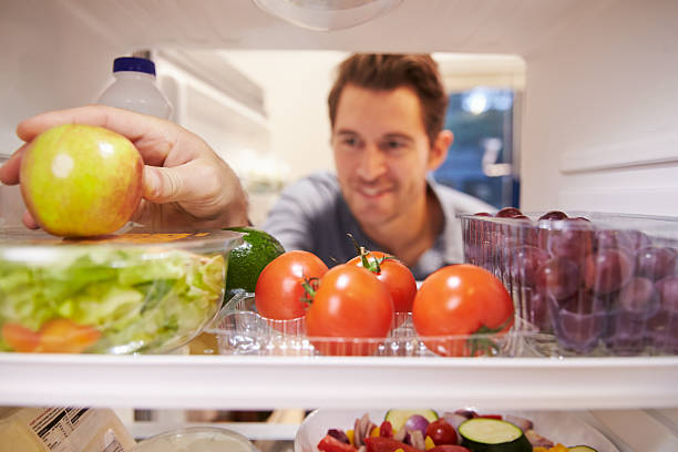 istock Man Looking Inside Fridge Full Of Food And Choosing Apple 527118003