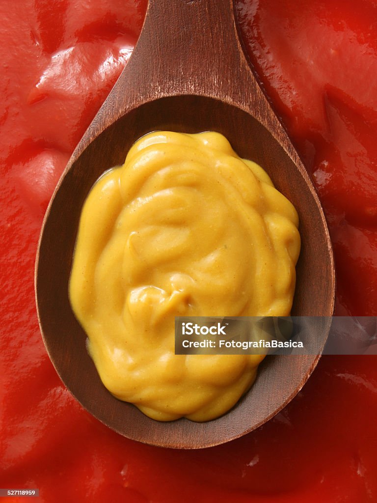 Mustard and ketchup Top view of wooden spoon with mustard spread over it and ketchup beneath it American Culture Stock Photo