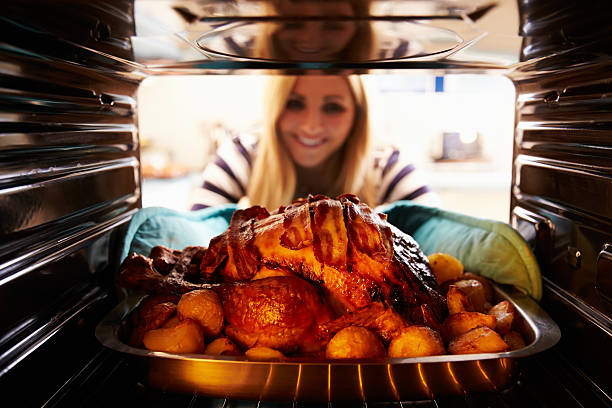 Woman Taking Roast Turkey Out Of The Oven Woman Taking Roast Turkey Out Of The Oven. Smiling smiling potato stock pictures, royalty-free photos & images