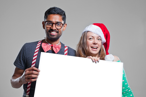 Two young attractive people holding a blank sign ready for your message.