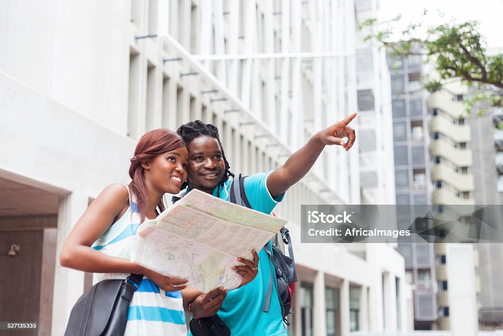 African male showing his girlfriend where they'll be going. African couple next to each other holding a map and the male is pointing out, showing her where he would like to go. Cape Town, Western Cape, South Africa. 20-24 Years Stock Photo