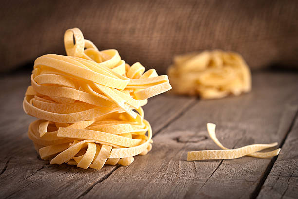 tagliatelle fatte in casa. uncooked pasta sul tavolo di legno - pasta noodles tagliatelle freshness foto e immagini stock