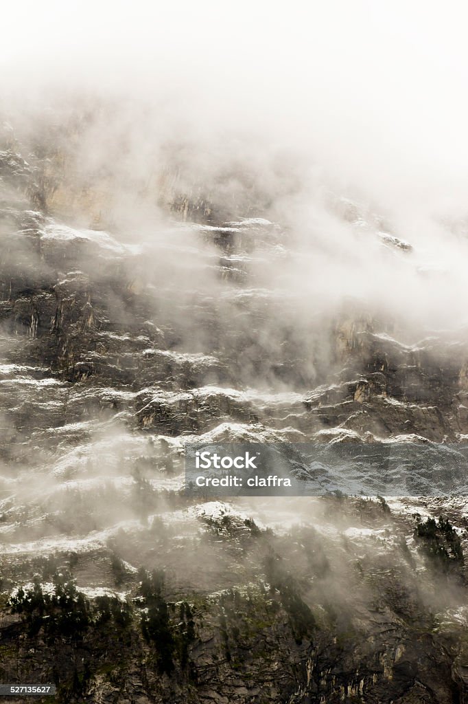 Mountain at sunrise Mountain slowly appearing through the mist, Grindelwald, Switzerland Aster Stock Photo