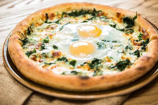 Margarita pizza with arugula and egg for breakfast, selective focus