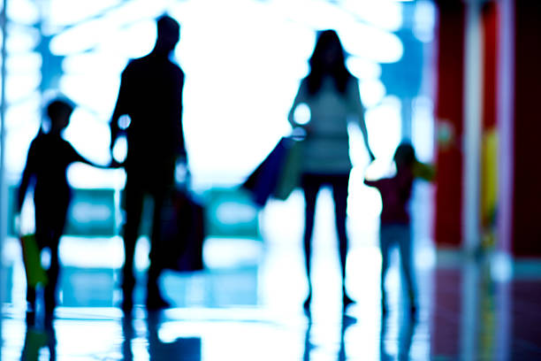 Defocused silhouettes of family with two children shopping together