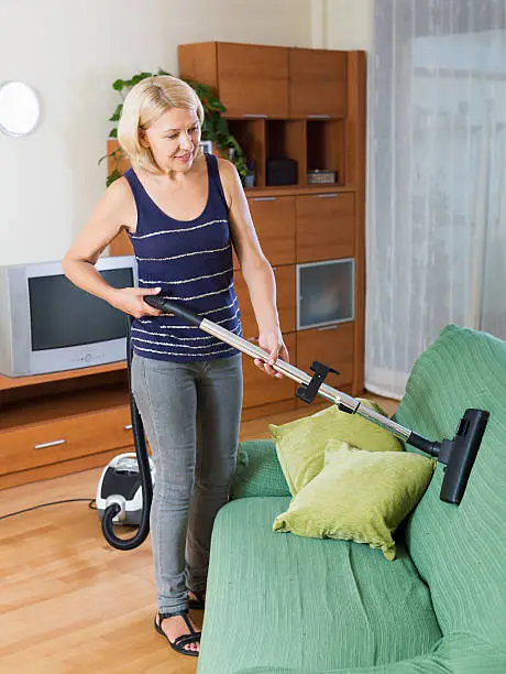 Photo of adult woman diligently cleaning living room